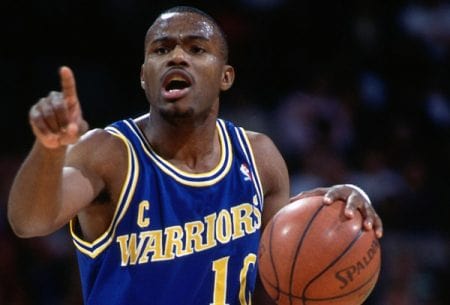 Tim Hardaway in his basketball jersey holding a basketball in his left hand.